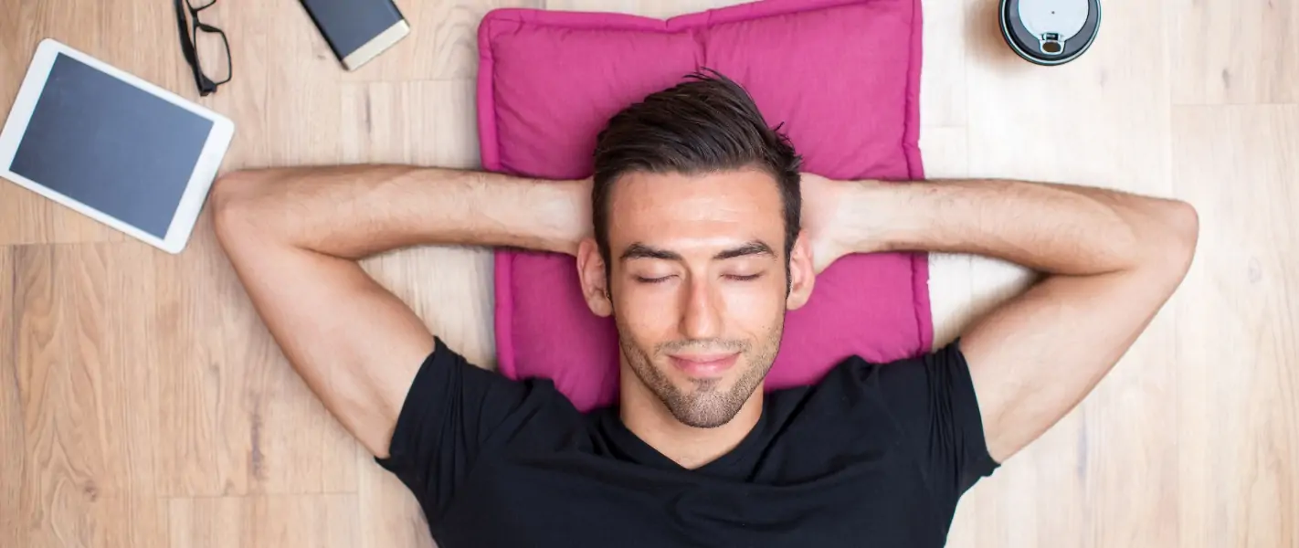 Mann entspannt mit Tablet und Handy neben sich.