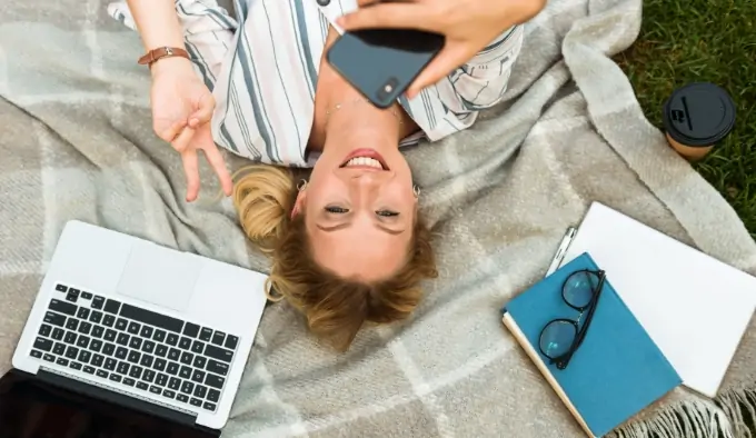 Frau mit Handy und Laptop zeigt Victory-Zeichen